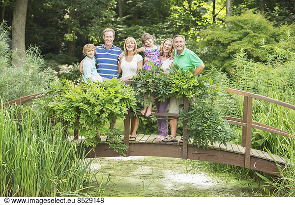 Mehrgenerationen-Familie auf Holzsteg über dem Teich stehend