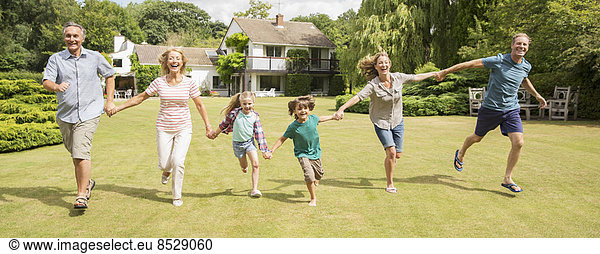 Mehrgenerationen-Familie beim Händchenhalten und Laufen im Gras