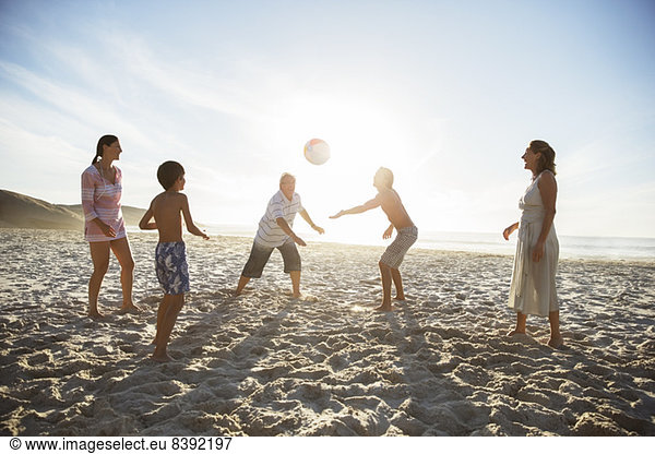 Mehrgenerationen-Familie beim Volleyball am Strand