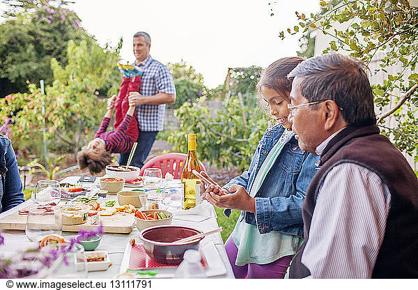 Mehrgenerationen-Familie genießt am Esstisch im Hinterhof