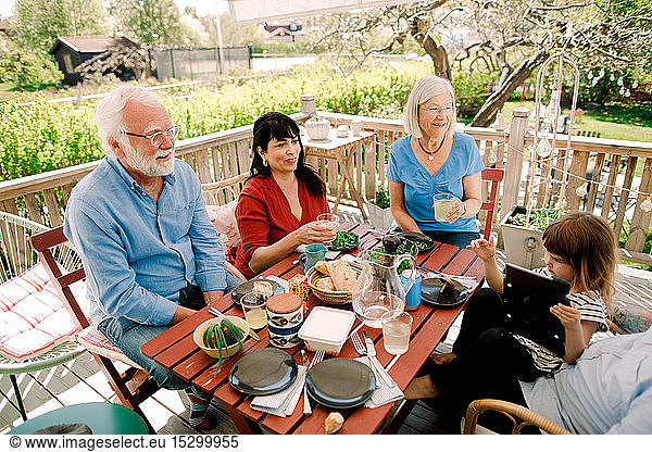 Mehrgenerationen-Familie genießt Essen am Tisch im Innenhof