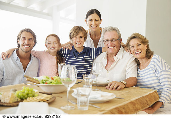 Mehrgenerationen-Familie lächelt gemeinsam bei Tisch