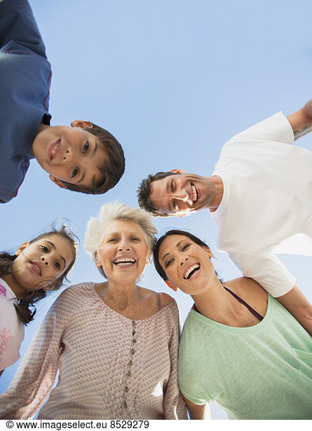 Mehrgenerationen-Familie lächelt vor blauem Himmel