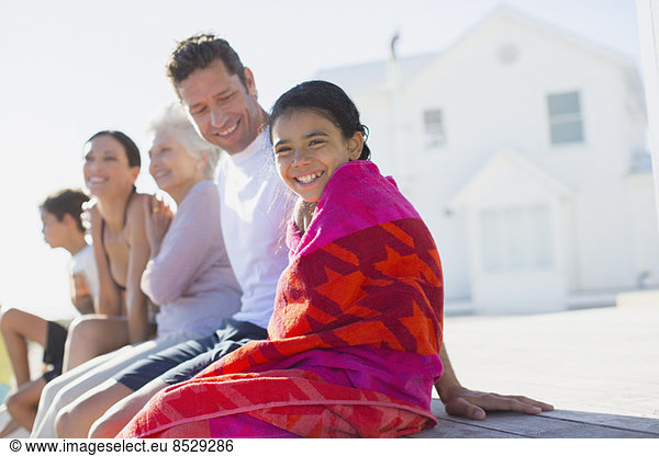 Mehrgenerationen-Familie vor dem Strandhaus sitzend
