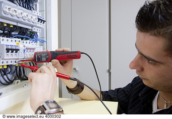 Meisterschüler der Elektriker mit dem Spannungsmesser an einem VDE ...