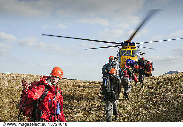 Members of Langdale/Ambleside Mountain Rescue team lead rescued walkers to safety  towards a waiting RAF Sea King helicopter after they had been rescued out of Dungeon Ghyll in the