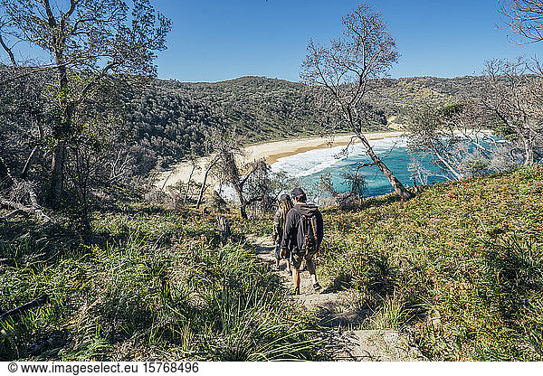 Men hiking on path to sunny remote ocean beach Jervis Bay Australia