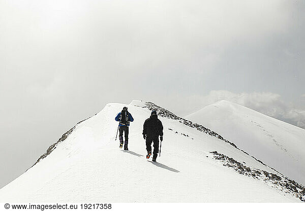 Men hiking with pole on mountain covered in snow
