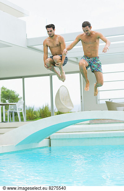 Men jumping into swimming pool