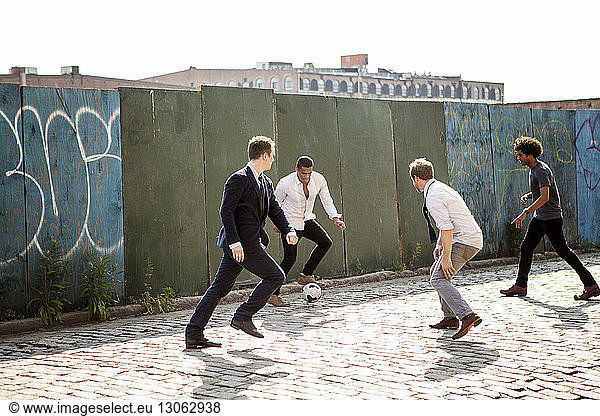 Men playing soccer by wall on street