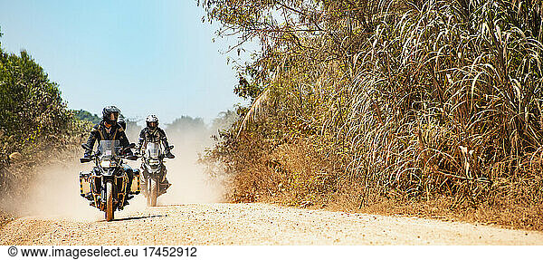 Men riding their adventure motorbikes on dusty road in Cambodia