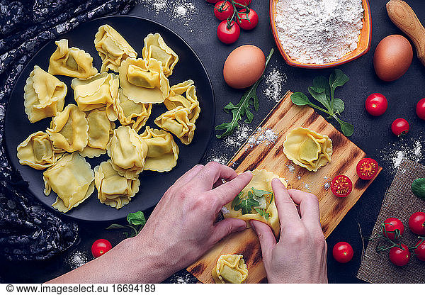 Men's hands prepare Italian pasta with ingredients. Gastronomic concept
