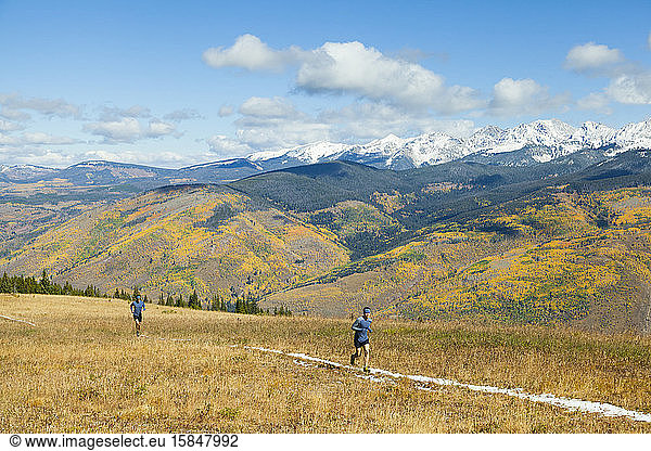 Men trail run on ridge below Gore Range mountains in Vail  Colorado