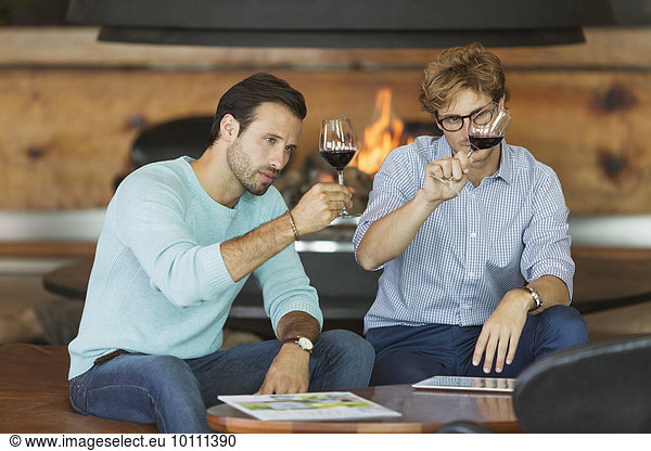 Men wine tasting red wine in winery tasting room