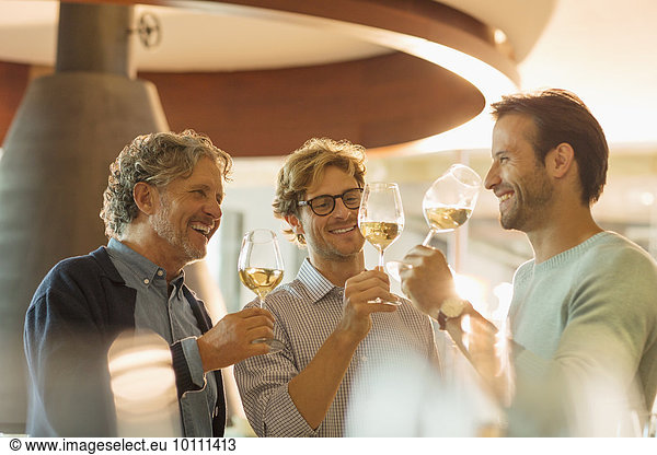Men wine tasting white wine in winery tasting room