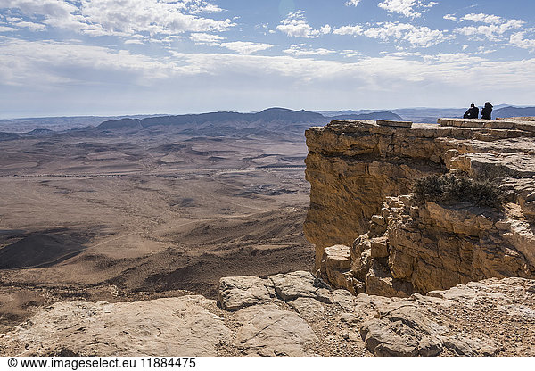 Menschen  die auf einem Felsvorsprung stehen und die Aussicht auf die zerklüftete Landschaft genießen  Ramon-Naturschutzgebiet; Mitzpe Ramon  Süddistrikt  Israel'.
