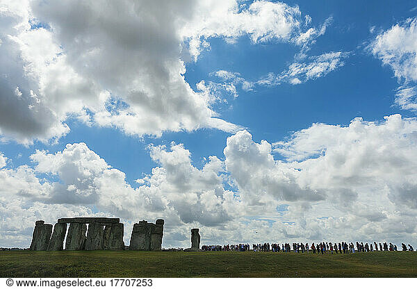 Menschen  die in einer Reihe stehen und sich um Stonehenge herum umsehen; Wiltshire  England