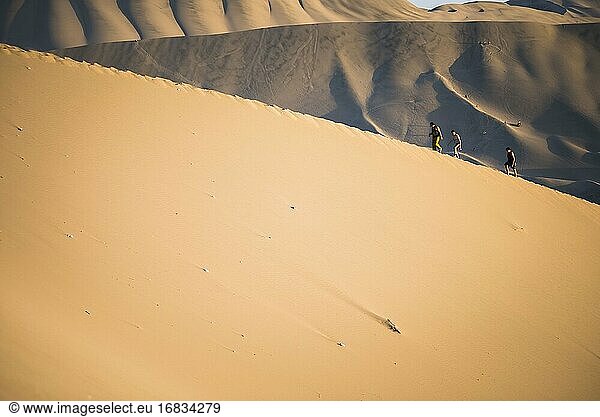 Menschen klettern auf Sanddünen  um den Sonnenuntergang über der Wüste in Huacachina  Region Ica  Peru  zu beobachten