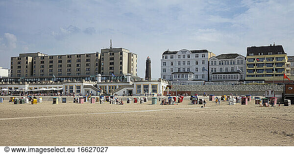 Menschen mit Kapuzenstühlen am Strand gegen Gebäude in der Stadt an einem sonnigen Tag
