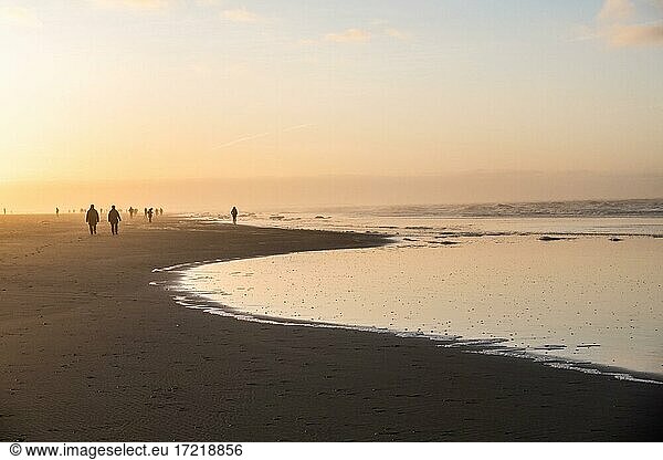 Menschen spazieren im Dunst bei Sonnenuntergang am Strand  Langeoog  Ostfriesische Inseln  Niedersachsen  Deutschland  Europa