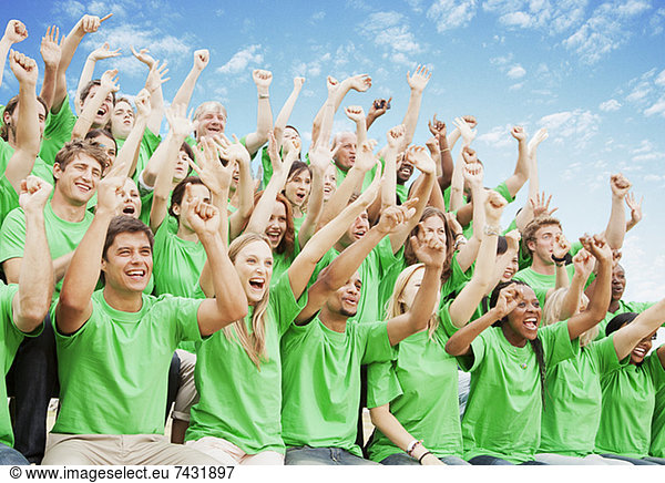 Menschenmenge in grünen T-Shirts jubelnd mit erhobenen Armen