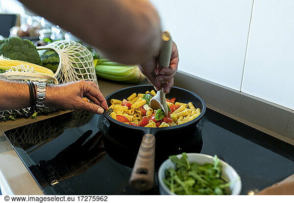 Menschliche Hand bei der Zubereitung von Nudeln in der Küche