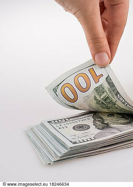 Menschliche Hand hält amerikanische Dollar-Banknoten an der Seite eines Modellhauses auf weißem Hintergrund