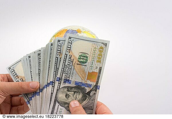 Menschliche Hand hält amerikanische Dollar-Banknoten an der Seite eines Modells Globus auf weißem Hintergrund