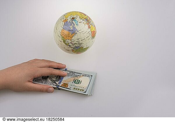 Menschliche Hand hält amerikanische Dollar-Banknoten an der Seite eines Modells Globus auf weißem Hintergrund