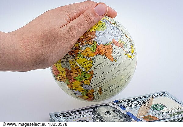 Menschliche Hand hält ein Modell Globus an der Seite eines amerikanischen Dollar-Banknoten auf weißem Hintergrund