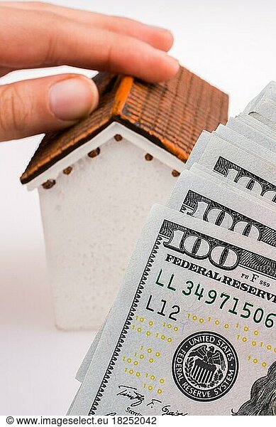 Menschliche Hand hält ein Modell Haus an der Seite einesAmerican Dollar Banknoten auf weißem Hintergrund