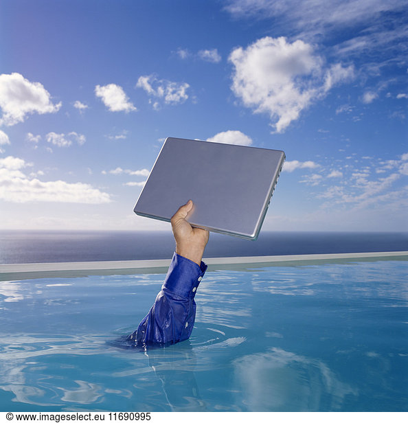 Menschlicher Arm in blauem Hemdsärmel im Schwimmbad  einen Laptop-Computer  Himmel und Wolken hochhaltend.