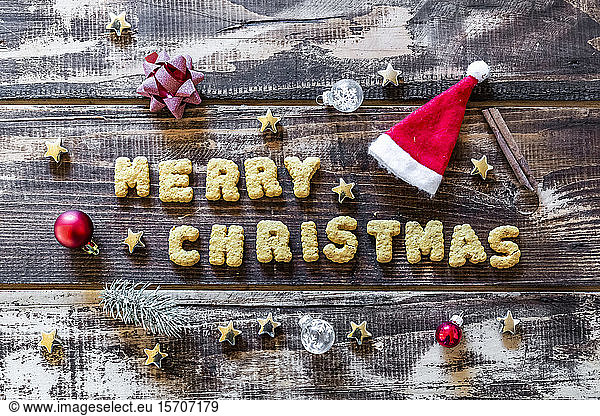 Merry Christmas written with cookies and Christmas decorations on wooden surface