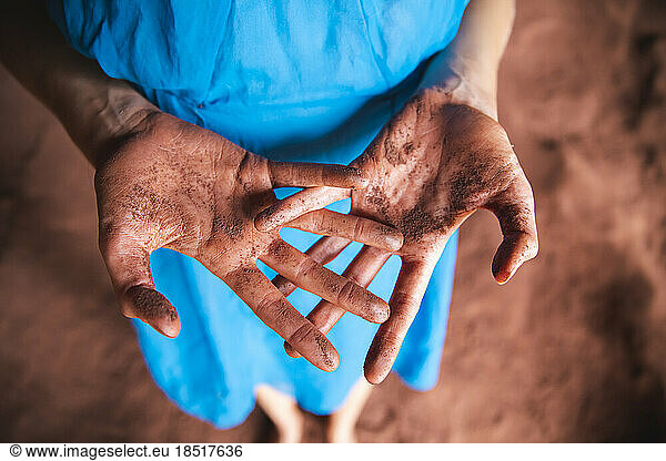 Messy hands of woman with red sand