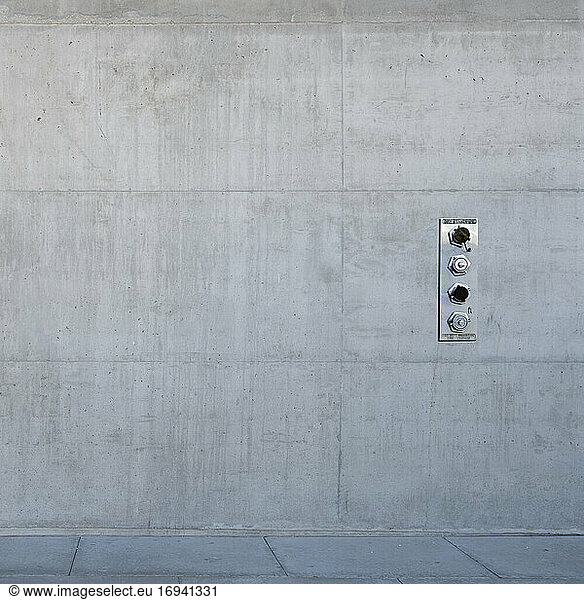 Metal control panel on concrete wall.