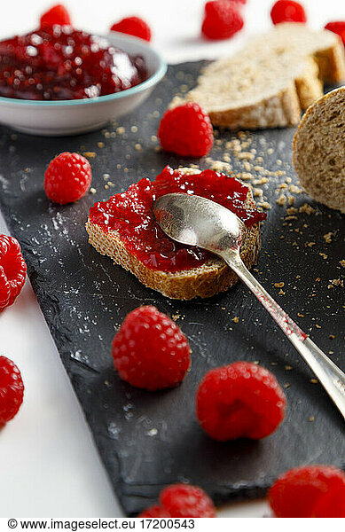 Metal spoon and slice of bread with raspberry jam