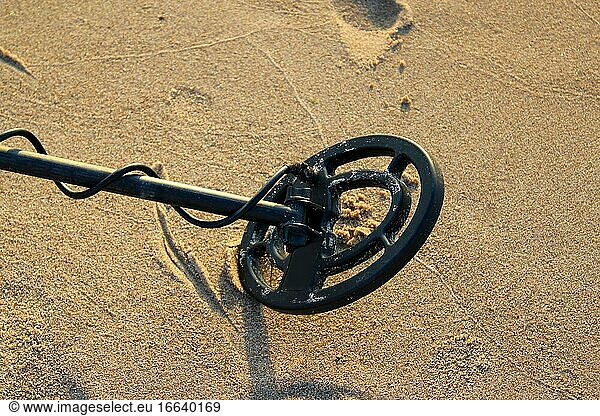 Metalldetektor mit runder Spule auf dem Sand.
