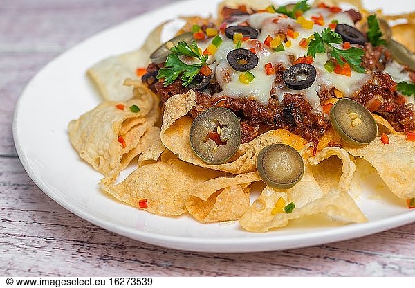 Mexican Famous Food Spicy Ground Beef Nachos. Heated crunchy tortilla chips with melted cheese and jalapeno served a snack food.