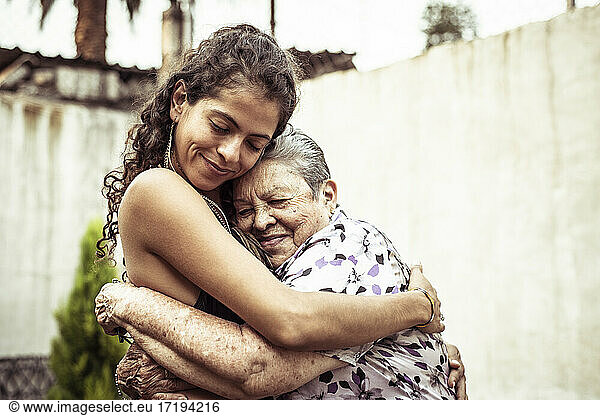 Mexican women smile in loving hug embrace on summer street Mecxico