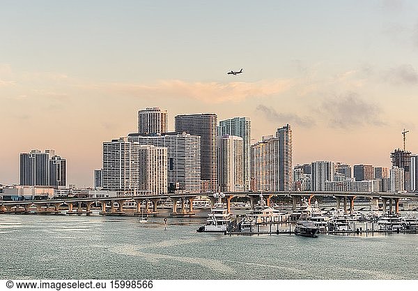 Miami  FL  United States - April 27  2019: Miami City Skyline at dawn viewed from Dodge Island at Biscayne Bay. Long traffic bridge and luxury yacht in the foreground.