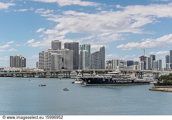 Miami  FL  United States - April 20  2019: Miami City Skyline viewed from Dodge Island at Biscayne Bay. Long traffic bridge and luxury yacht in the foreground.