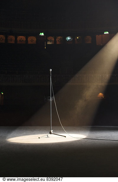 Microphone in spotlight on empty theater stage