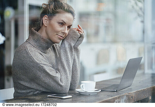 Mid adult business person contemplating while sitting by cafe window