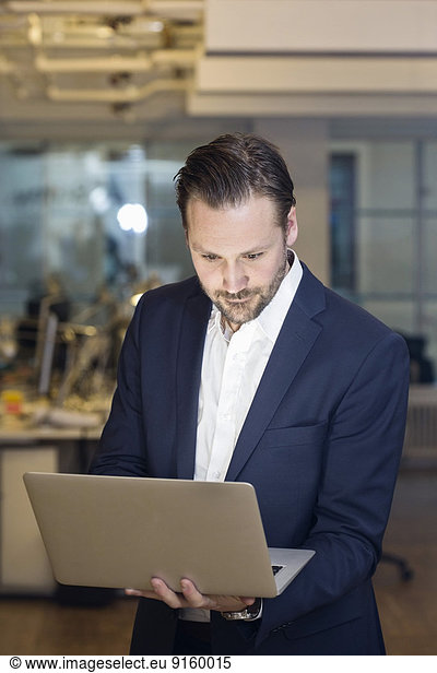Mid adult businessman using laptop in office
