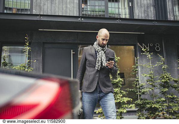 Mid adult businessman using mobile phone against building