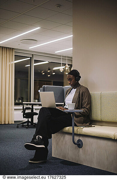 Mid adult businesswoman working on laptop in office at night