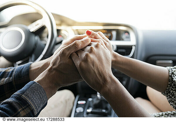 Mid adult couple holding hands while sitting in car