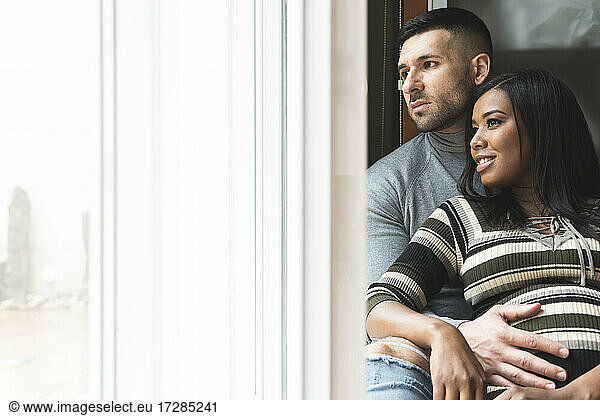Mid adult couple looking away through window at home