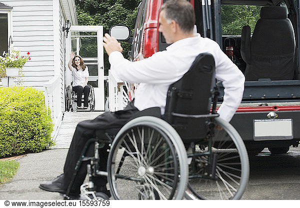 Mid adult couple sitting in wheelchairs Husband with a Spinal Cord Injury waving hands to each other