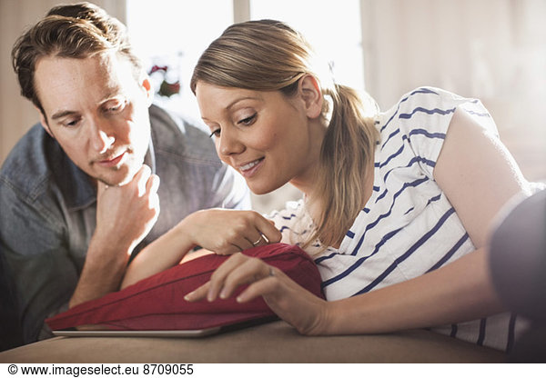 Mid adult couple using digital tablet in house